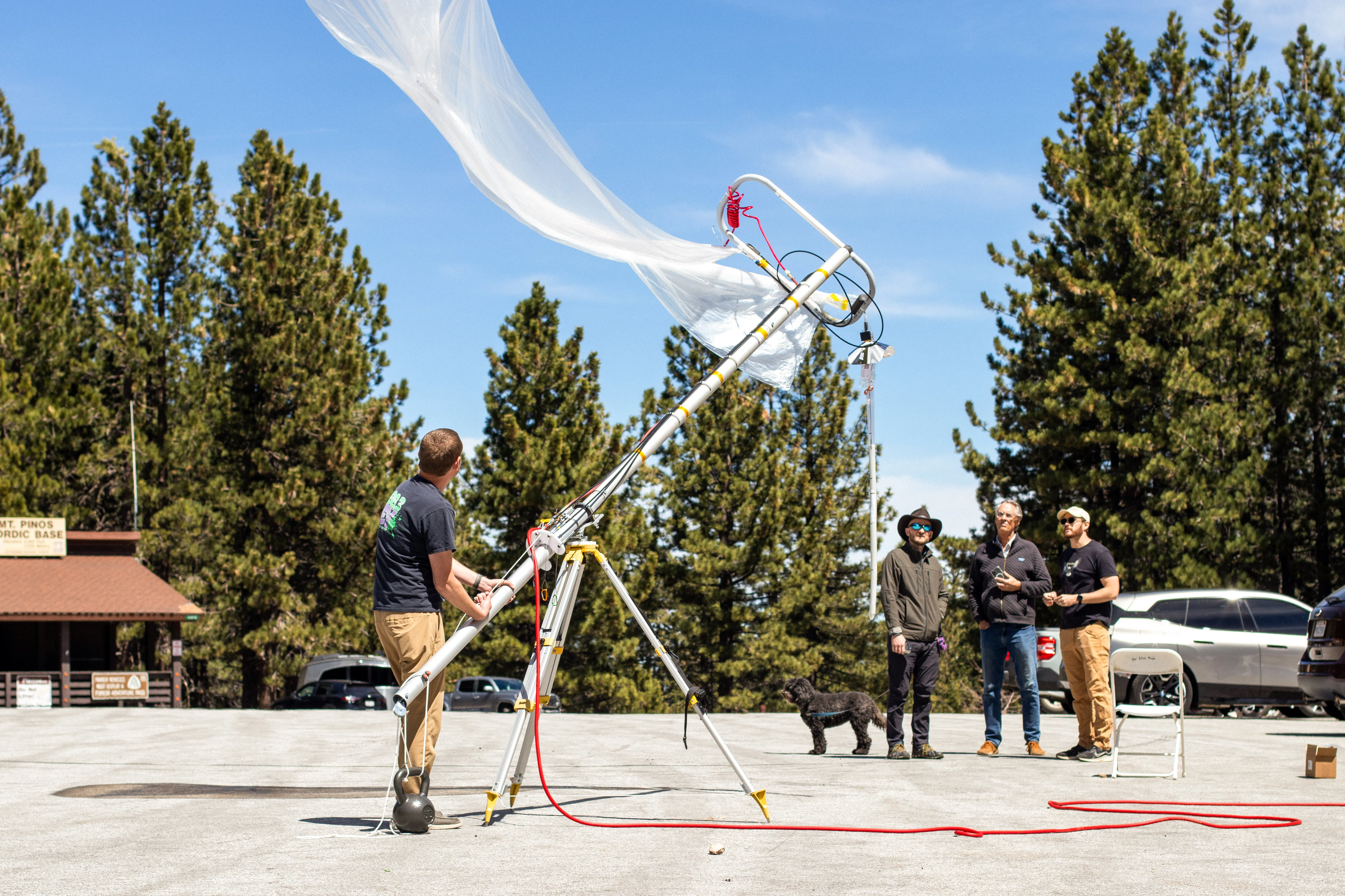 A launch operator releases a weather balloon while community members watch