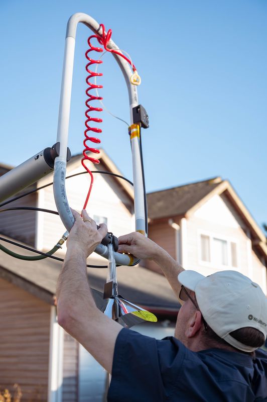 A launch operator in a white cap attaching balloon components to the top of the launch rig.
